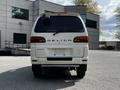 A white 2003 Mitsubishi Delica 7 Passenger Van is parked facing the viewer showcasing its rear design with the brand name visible on the back