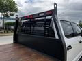 A white 2020 Ford F-350 with a black flatbed featuring a protective grille and red lights mounted on the back