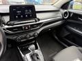 Interior view of a 2021 Kia Forte featuring a touchscreen display along with controls for climate and audio on the center console and a gear shifter on the floor