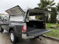 A gray 2015 Toyota Tacoma with its rear bed cover open and two side panels lifted revealing the truck bed and interior space