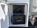 Open storage compartment of a 2008 International DuraStar containing a crate a hose and various tools