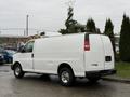 A white 2009 Chevrolet Express van with a simple rear design and chrome wheels parked on a paved surface