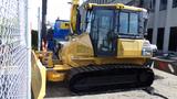 A yellow 2013 Komatsu D37PX-22 bulldozer with a plow attachment and rubber tracks positioned on a construction site