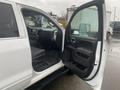 A 2015 GMC Sierra 1500 with the driver's side door open showing the interior dashboard and seating area