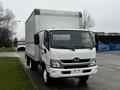 A white 2018 Hino 195 truck with a large cargo box on the back is parked on a street facing forward