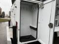 An open storage compartment on a 2024 RAM 5500 with a textured floor and hooks on the side for tools or equipment