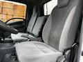 The interior of a 2018 Isuzu NRR featuring two gray cloth seats with simple designs and a steering wheel in the foreground