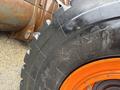 Close-up of a tire from a 2018 Doosan DL300-5 loader featuring a rugged tread pattern and orange rim with visible water droplets on the surface