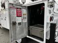 A 2016 Ford F-550 utility truck with an open metal equipment compartment displaying safety warnings and a stainless steel interior