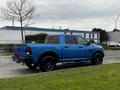 A blue 2021 RAM 1500 Classic truck with black accents is parked on the side of a road showcasing its distinct design and features