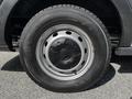 Close-up of a black wheel and tire of a 2015 Ford Transit featuring several circular holes in the rim and a textured tire tread