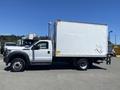 A white 2015 Ford F-450 Super Duty truck with a boxy cargo area and a single cab, parked to the side