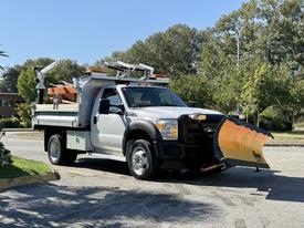 A 2011 Ford F-550 truck with a front-mounted snow plow and equipment on the bed designed for snow removal and maintenance tasks