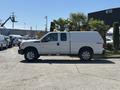 A 2014 Ford F-250 SD pickup truck in white with a covered bed and four-wheel drive features parked beside greenery.