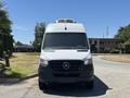 A 2019 Mercedes-Benz Sprinter van with a white exterior and a prominent front grille is parked facing the viewer