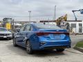 A blue 2021 Kia Forte parked with a sleek design featuring a sporty rear and modern tail lights