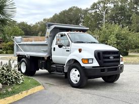 A white 2004 Ford F-750 dump truck with an open bed and hydraulic lift, featuring a black front grille and headlights