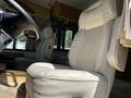 Two beige leather captain chairs inside a 2000 Ford Motorhome with a dashboard and interior features visible in the background