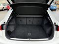 A 2024 Audi Q3 with an open trunk showcasing a spacious black cargo area featuring hooks and a flat floor