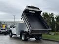 A 2021 Ford F-550 dump truck with its bed raised displaying an empty cargo area and a silver body