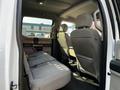 Interior view of a 2021 Ford F-550 showing two rows of seats in gray fabric with a central armrest in the front row
