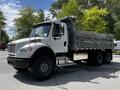 A 2010 Freightliner M2 106 dump truck with a silver dump bed and black tires parked on a road