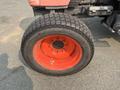 Front tire of a 2010 Kubota M6040 tractor featuring an orange rim and a textured black tire tread