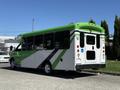 A 2013 Chevrolet Express bus with a green and white color scheme featuring black accents and large windows