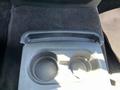 A black cup holder with two circular recesses designed for beverages in the center console of a 2014 Ford F-150