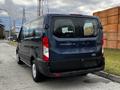 A blue 2020 Ford Transit van parked on the side of the road with a rear view showing the model name and taillights