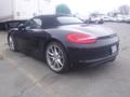 A black 2016 Porsche Boxster with a convertible top and alloy wheels positioned at an angle showing its sleek design and rear features