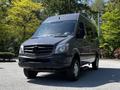 A 2017 Mercedes-Benz Sprinter van in a dark color with a sleek design and the Mercedes logo prominently displayed on the front