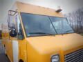 A yellow 2008 Freightliner MT45 chassis with a large windshield a side mirror and a light on the roof