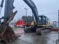 A 2014 John Deere 350G excavator with a large bucket attachment is parked on a concrete surface