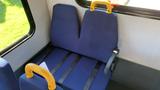 Two blue fabric seats with yellow handles and safety straps inside a vehicle