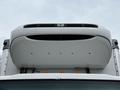 A close-up view of the front grille and hood of a 2018 Isuzu NRR truck featuring a white exterior and a black grille with the Isuzu logo in the center