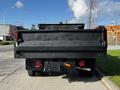 A black 2018 Ford F-550 dump truck viewed from the rear with a flatbed and taillights prominently visible