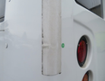 2020 Chevrolet Express showing a dent on the rear corner with a green adhesive label and a round red taillight on the side