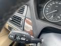 Close-up of the dashboard controls of a 2009 BMW X5 featuring the speedometer and various knobs for climate and light settings
