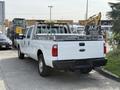 A white 2011 Ford F-350 Super Duty truck with a silver ladder rack in the bed and a long cab design