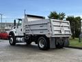 A 2011 International WorkStar dump truck in white with a metal bed and black tires parked on a surface with a slight sheen from moisture