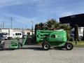 A green 2015 JLG 450AJ aerial lift with a work platform and extendable boom parked next to vehicles