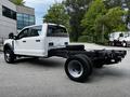 A 2024 Ford F-550 chassis cab truck with a white exterior features dual rear wheels and a large empty truck bed showing the frame and suspension system