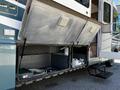 A 2000 Ford Motorhome with open storage compartments revealing cleaning supplies and hoses inside