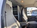 Interior view of a 2012 GMC Savana showing two gray seats in the front cabin with storage compartments behind them