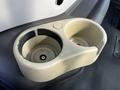 A beige plastic cup holder designed for a 2005 Volvo VND 122 with two compartments and a circular button on the surface