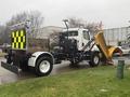 A 2016 Freightliner 108SD truck with a yellow snowplow attached to the front and a black and yellow reflective safety panel on the back