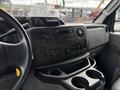 Interior dashboard of a 2017 Ford Econoline featuring controls for audio and climate along with cup holders and storage compartments