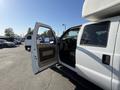 A white 2014 Ford F-350 SD with an open driver's side door showcasing a spacious interior and a prominent dashboard