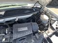 Engine compartment of a 2012 Chevrolet Express showing various components including the air filter intake battery and fluid reservoirs